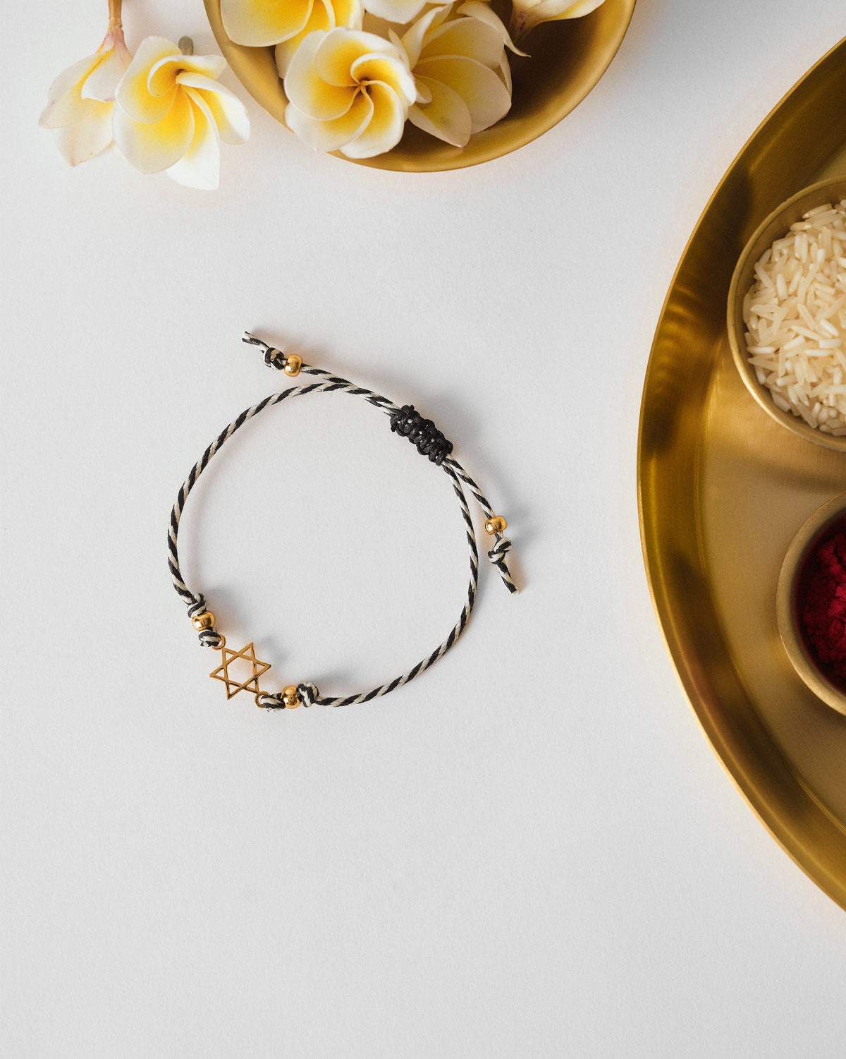 Sitara Rakhi in charcoal and white stripes with a gold star, laid flat.
