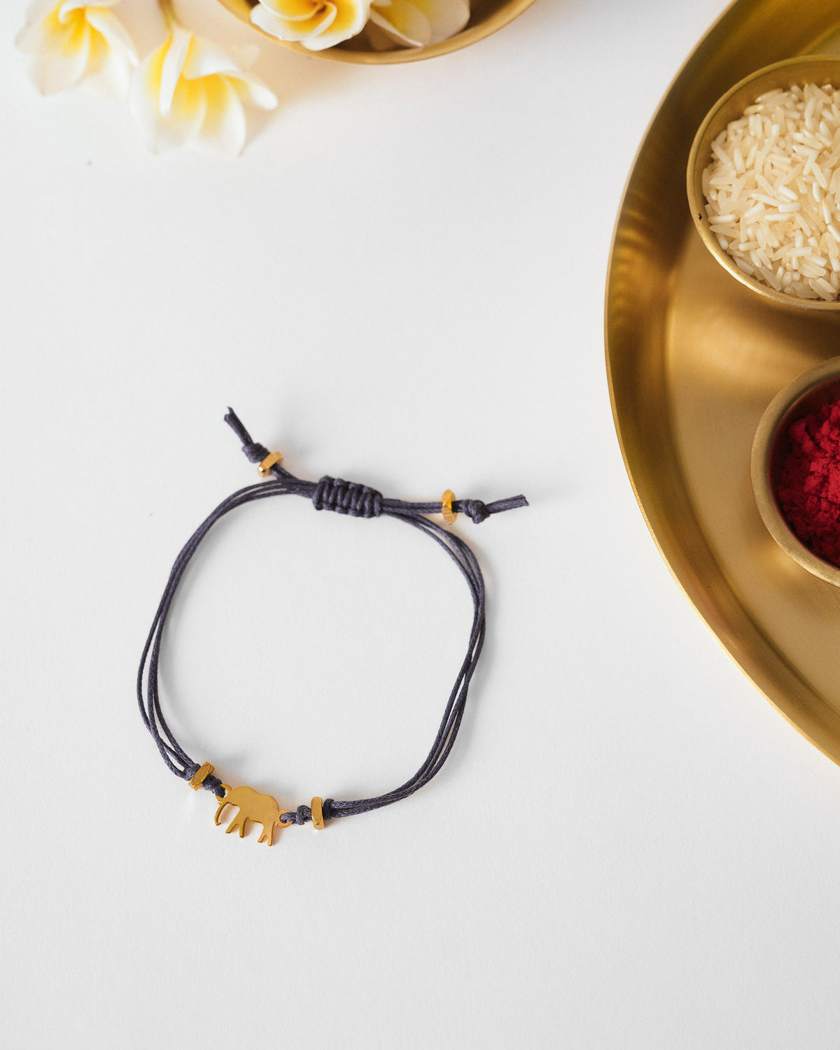Blue Ele Rakhi with a gold elephant charm laid flat.
