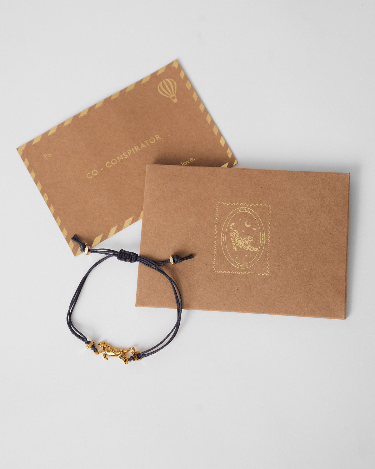 Blue tiger rakhi with kraft gift envelopes showing a tiger stamp.