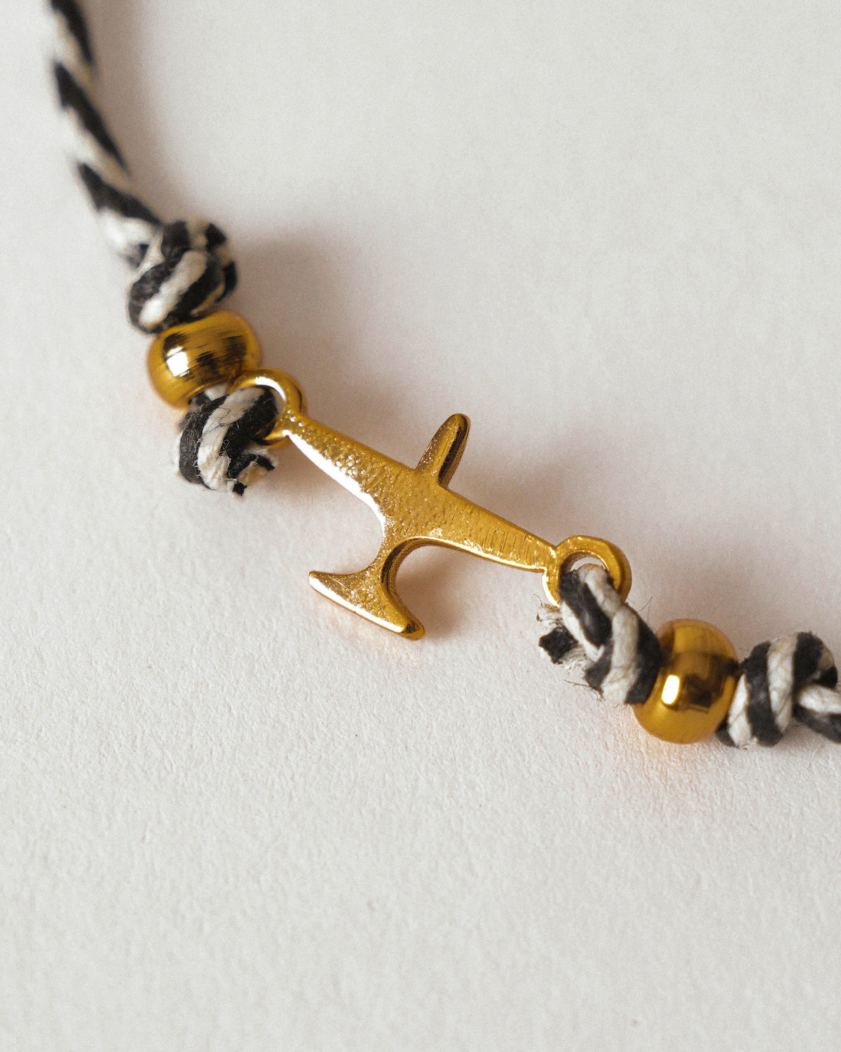Close-up of Airplane Rakhi showing a gold airplane charm on black and white cord.