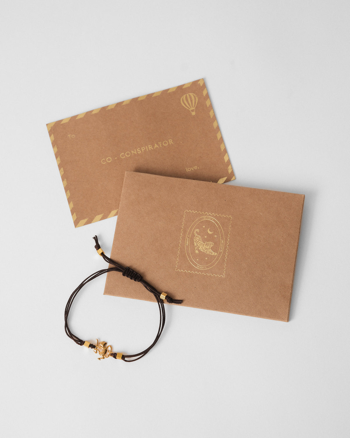 Brown Monkey Rakhi beside a kraft gift envelope and card.