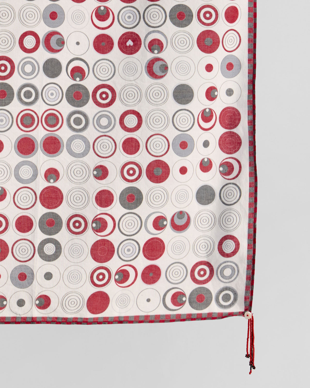 Close-up of Ripple scarf corner showing red and grey circles and a red tassel.