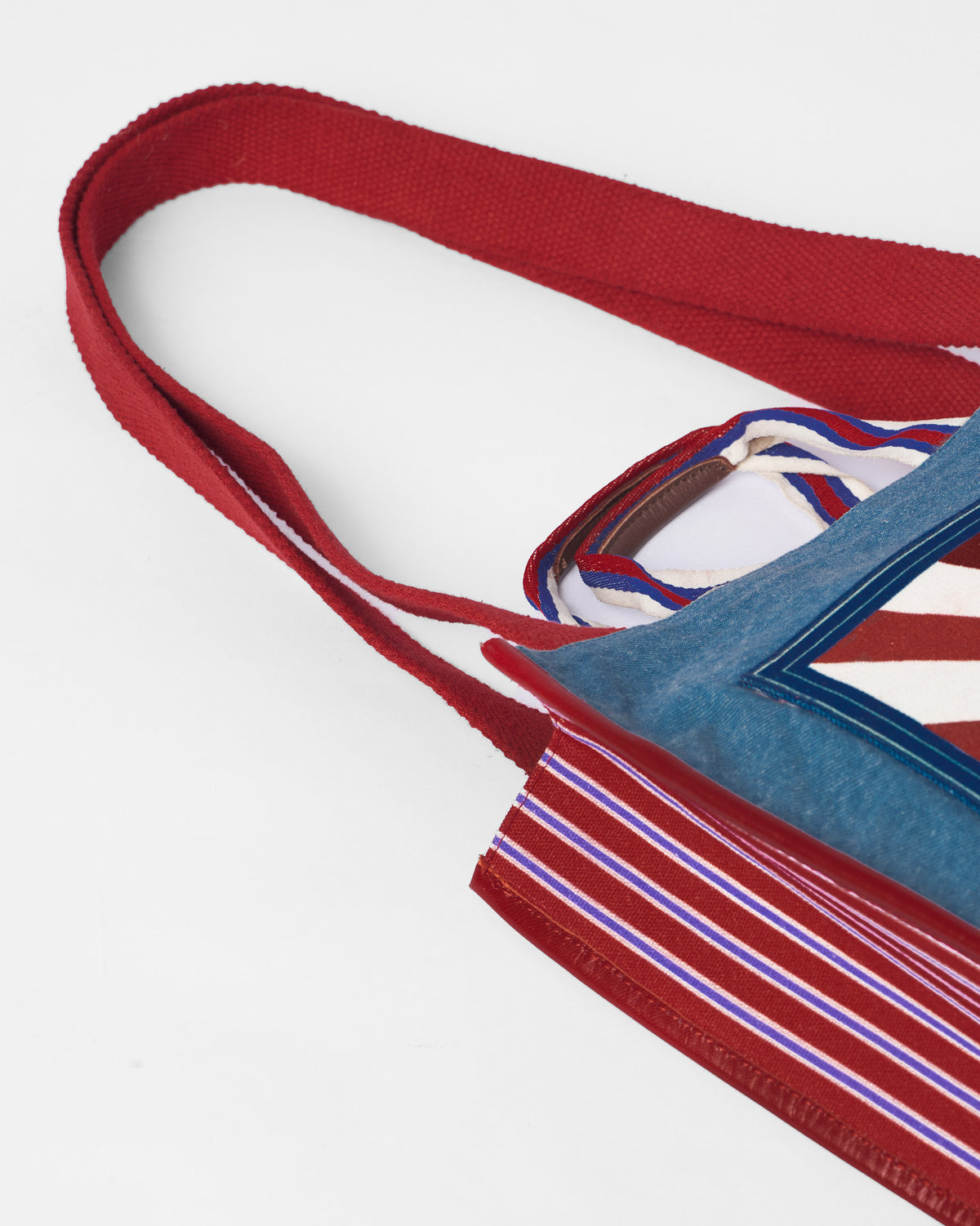 Close-up of a Nico Matchbox tote showing red straps and a striped side.