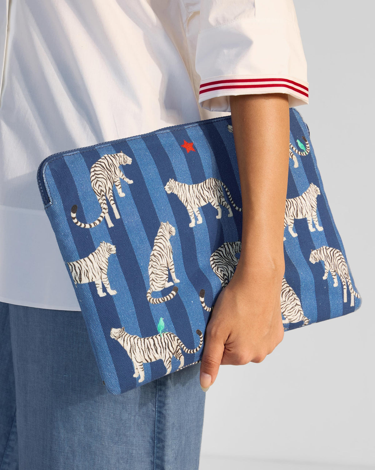 Person holding the Berber Laptop Sleeve in blue with white tiger print under one arm.