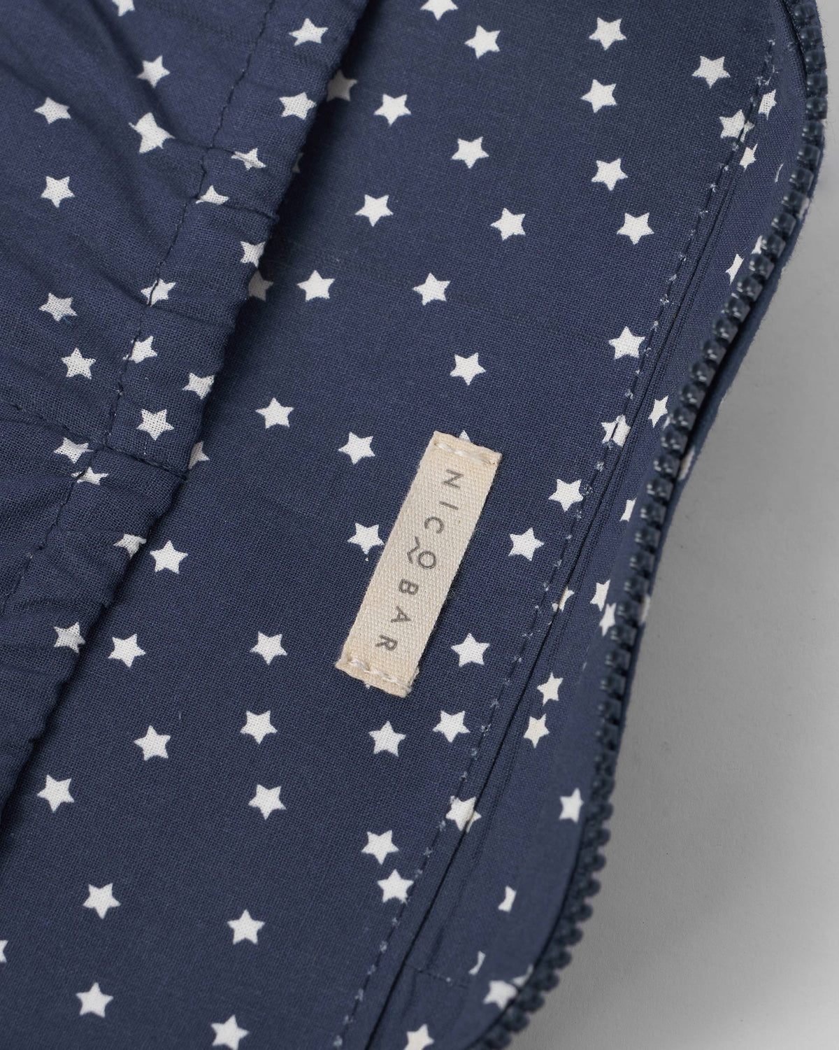 Close-up of the Nicobar label inside a navy Gadget Pouch with star lining.