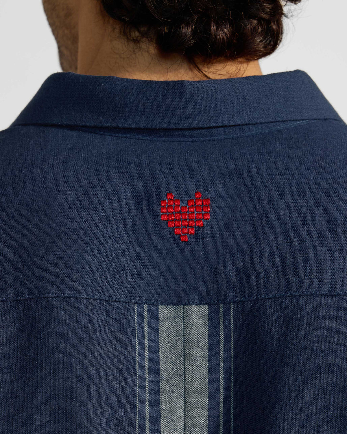 Close-up of a red pixel heart embroidered on a navy Rewa shirt.