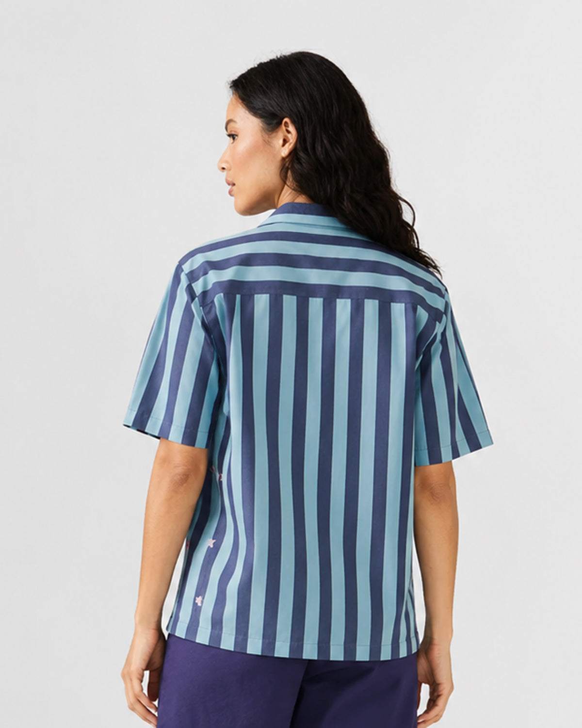 Back of a blue striped Nilambar shirt with embroidered fish motifs.