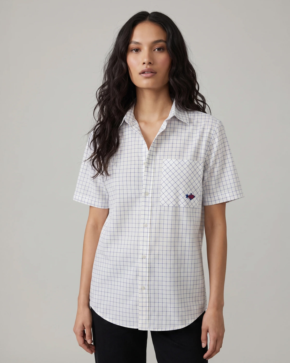 Person wearing a navy and white check Parikrama shirt with a fish on the pocket.