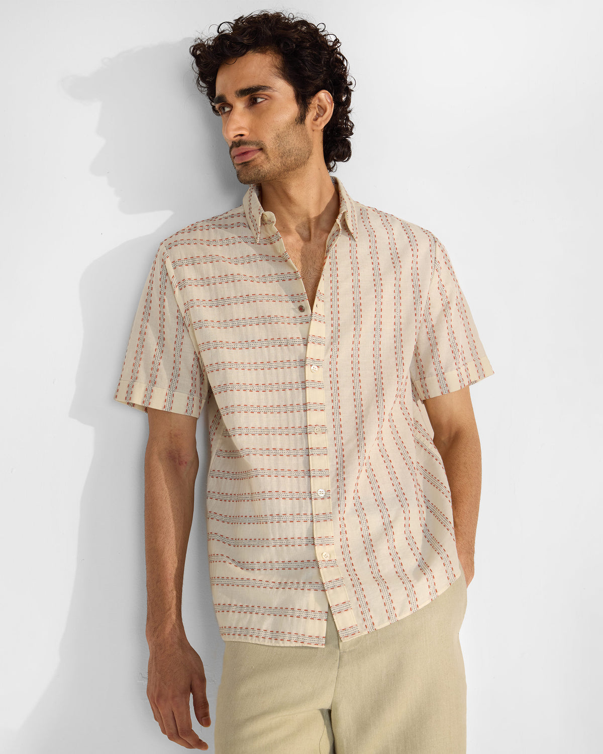 Person wearing an ivory Half Sleeves Shirt with thin dashed orange and grey stripes.
