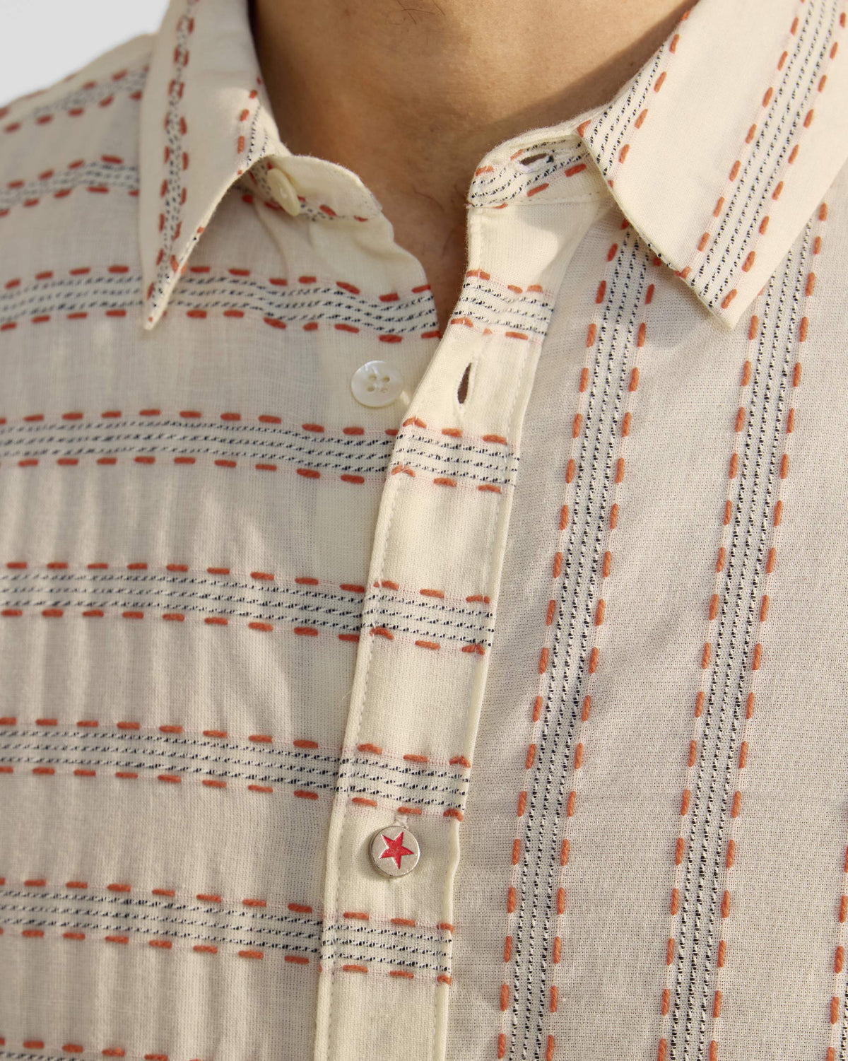 Close-up of an ivory Half Sleeves Shirt showing dashed stitching and a red star button.