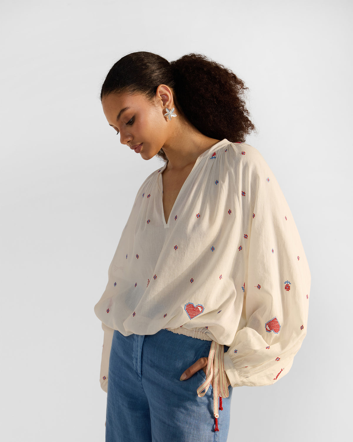 Person wearing an ivory Tahi top with a drawstring hem and heart embroidery.