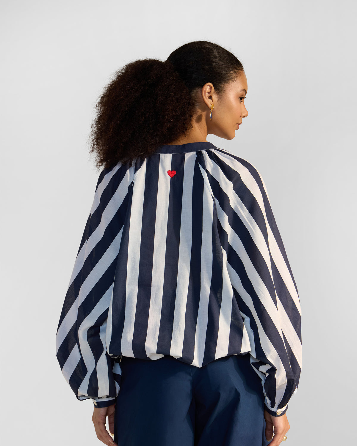 Back of a navy and white striped Zaya top with a red heart embroidery.
