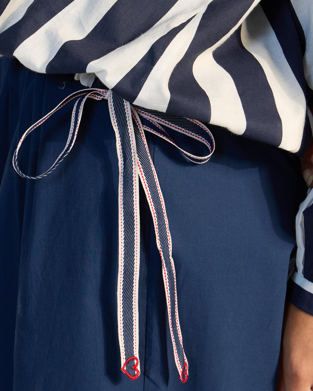Close-up of a Zaya top drawstring with a red heart tip.