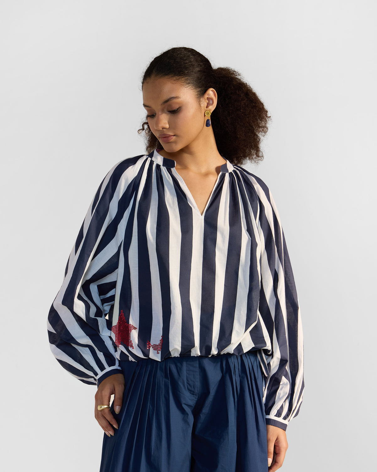Person wearing a navy and white striped Zaya top with a red star.