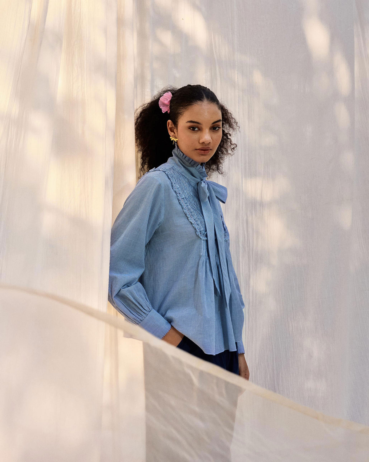 Person wearing a blue check Lona necktie top with a bow collar.