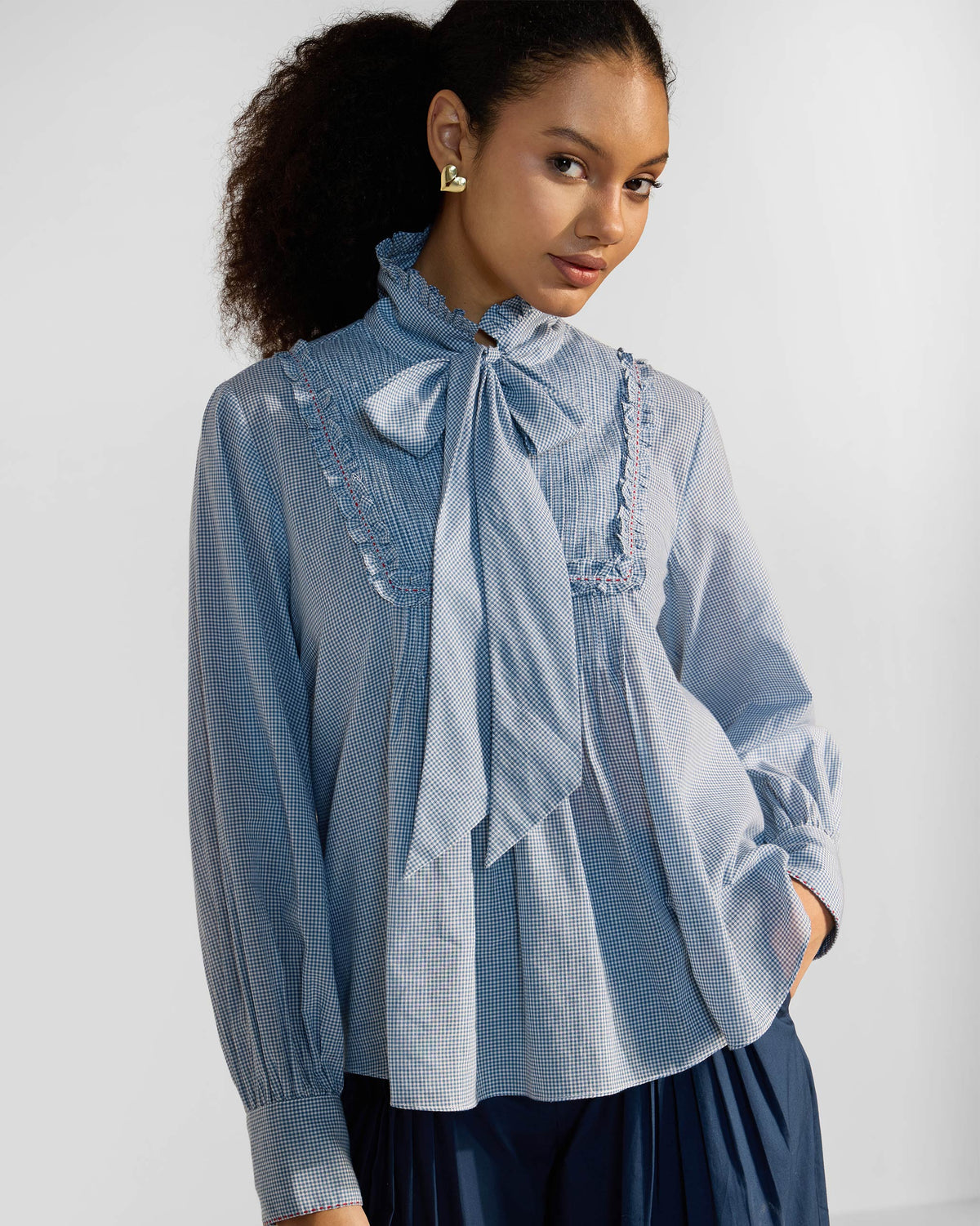 Person wearing a blue check Lona top with a necktie bow.
