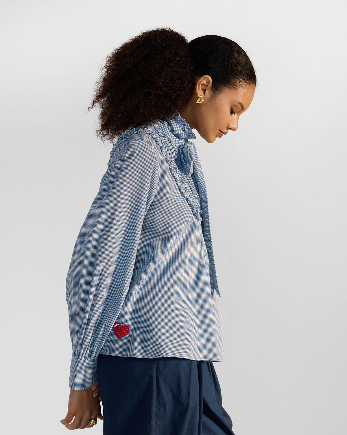 Side view of a blue check Lona top with a red heart near the hem.