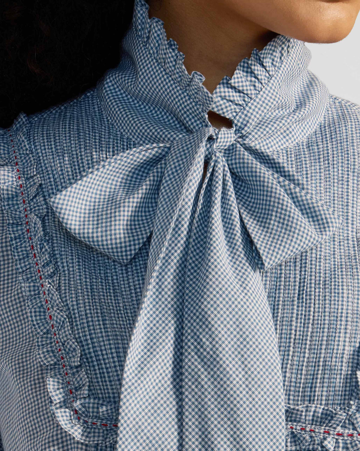 Close-up of a blue check Lona top necktie and ruffled collar.
