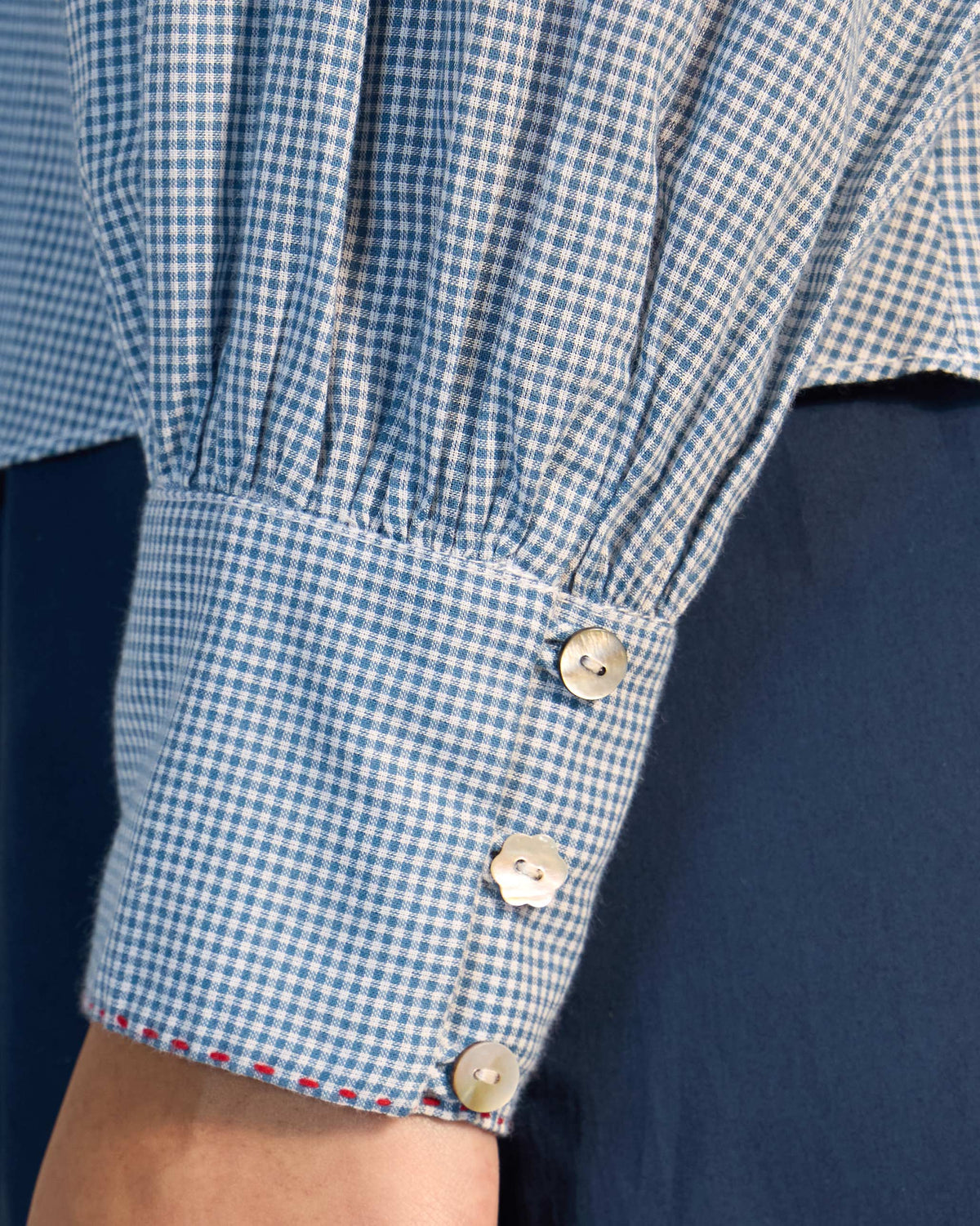 Close-up of a blue check Lona top cuff with flower buttons.