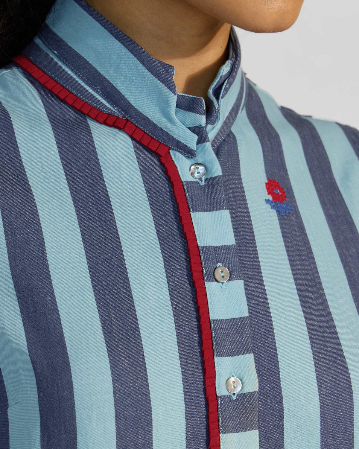 Close-up of a Bargi jumpsuit placket with red trim and buttons.