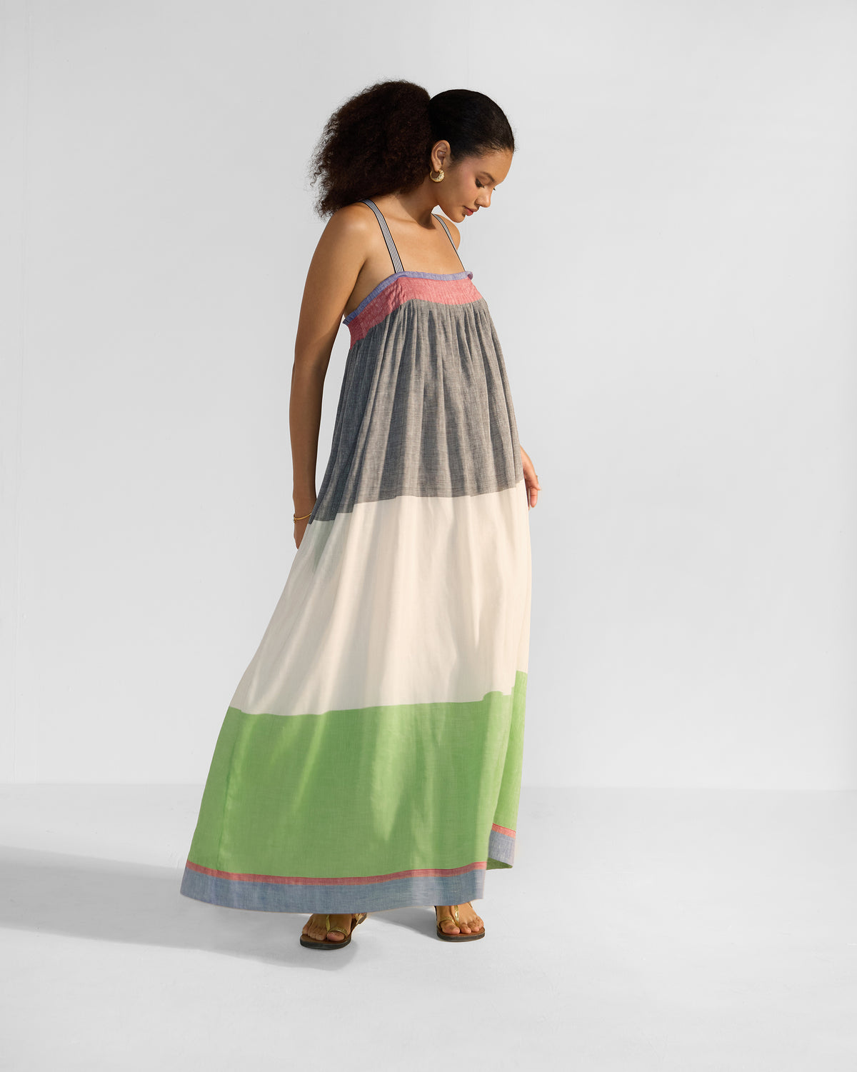 Person wearing a tiered multicolour Bina maxi dress in charcoal, cream, and green.