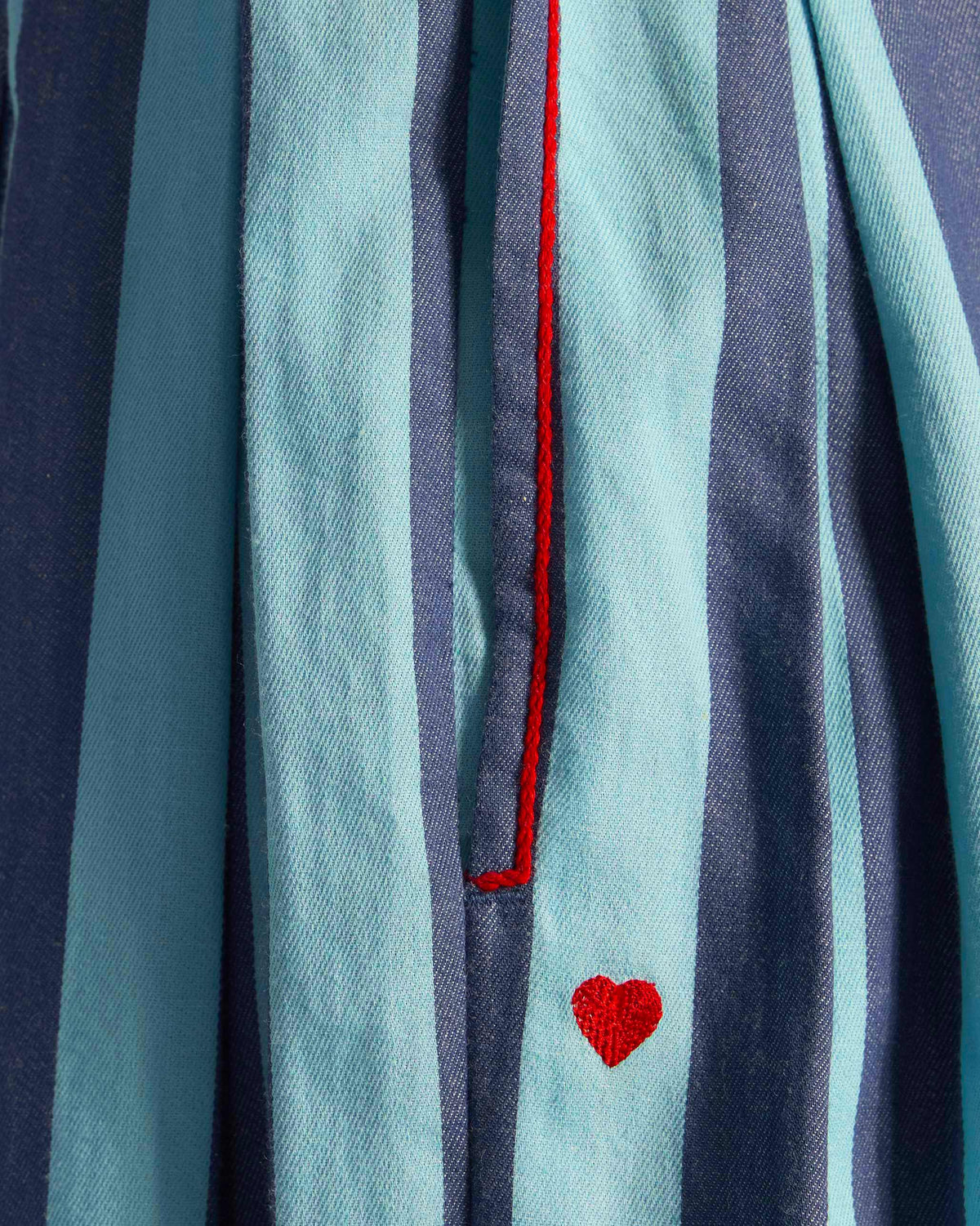 Close-up of blue striped salem pants showing a side pocket and red heart.