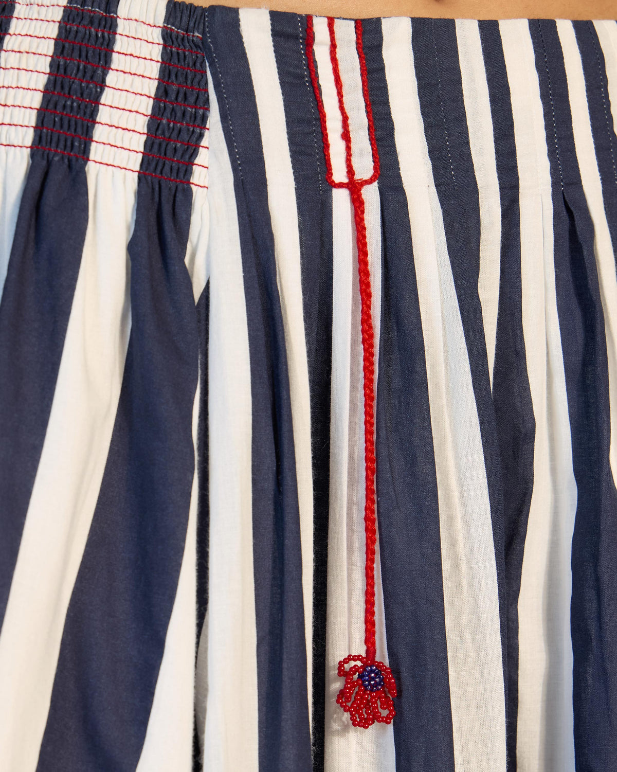Close-up of a Reyat skirt waistband with a red beaded flower tassel.