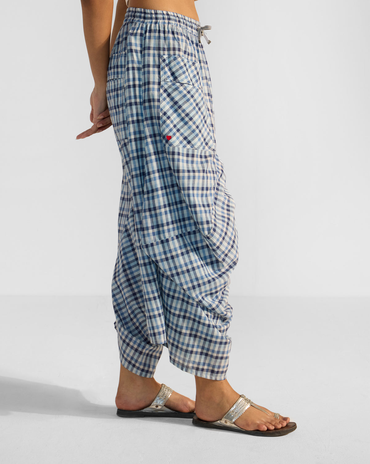 Side view of blue and white checked Yoka trousers with a red heart on the pocket.