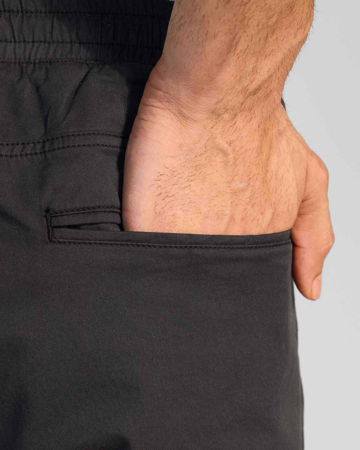 Close-up of a black Pravah trouser side pocket with a hand resting inside.