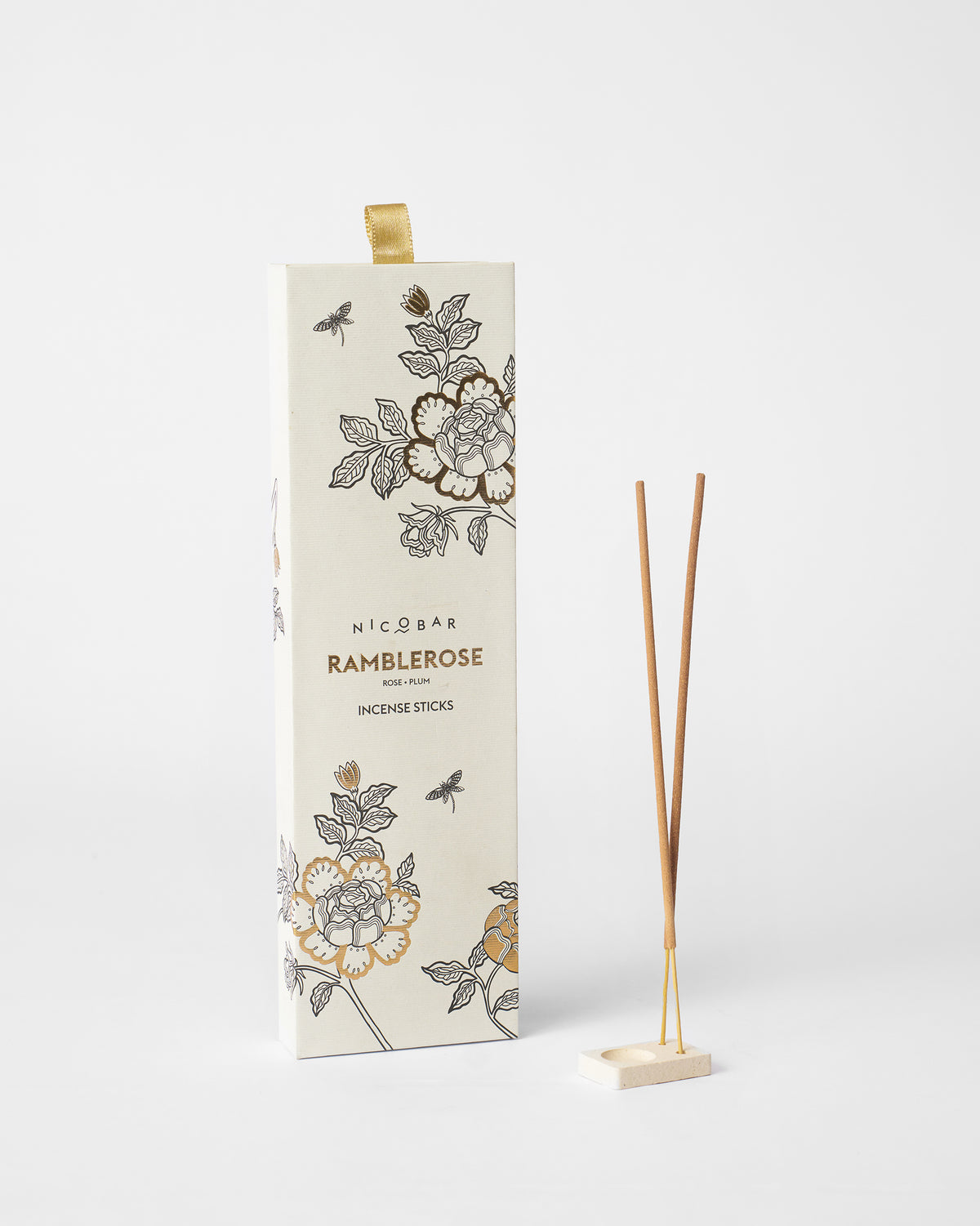 Ramblerose incense box beside two sticks in a square ceramic holder.