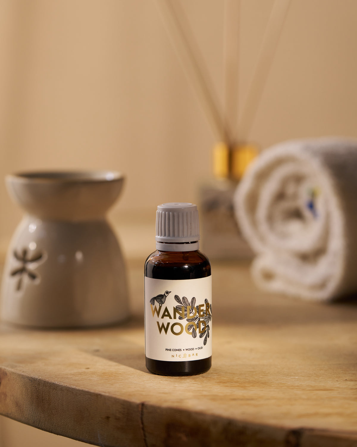 Wanderwood oil vial on wood near a ceramic oil burner.
