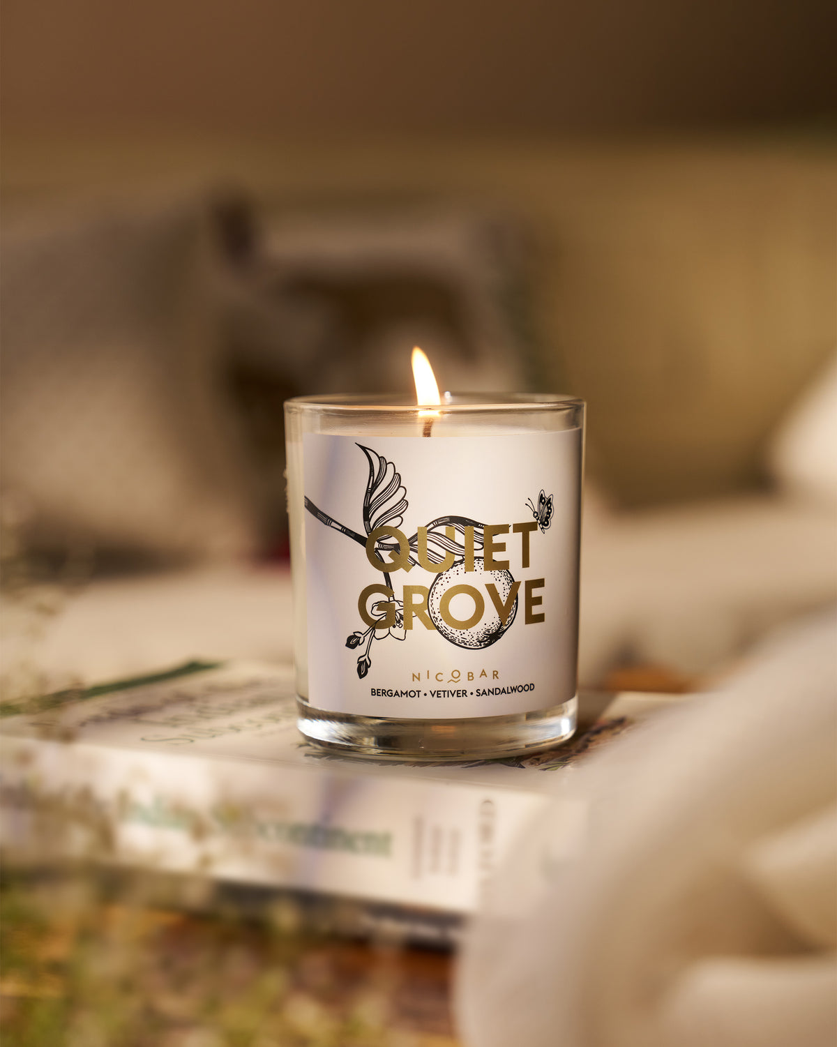 Lit Quiet Grove Candle in a clear glass.