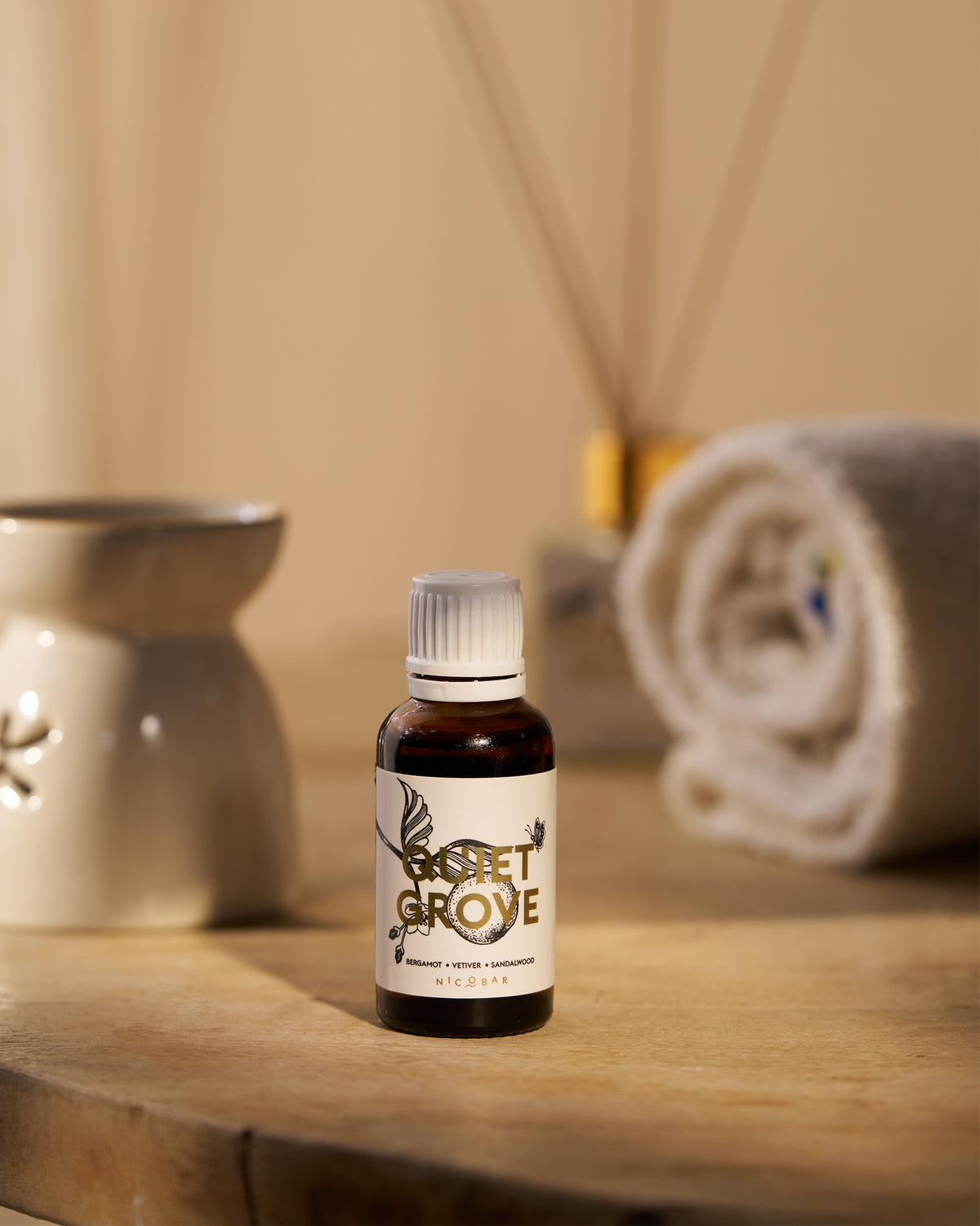 Amber Quiet Grove oil vial with bergamot label on a wooden surface.