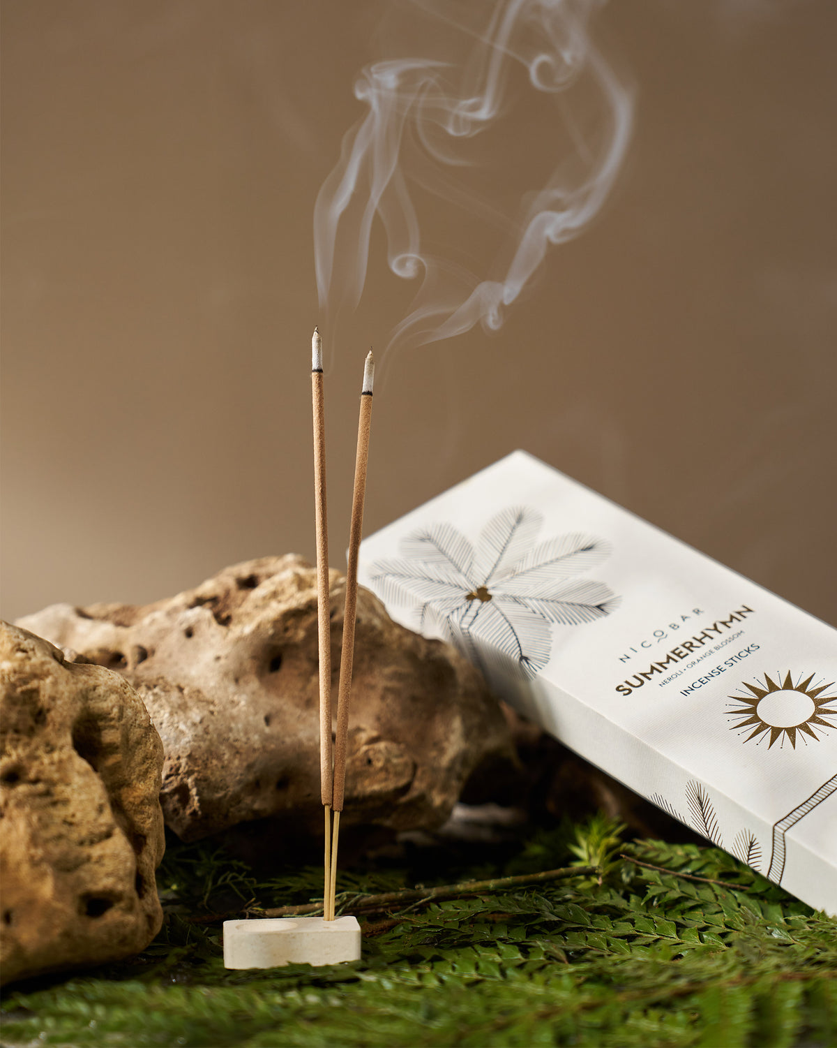 Summerhymn Incense Sticks burning in a stone holder beside their box.