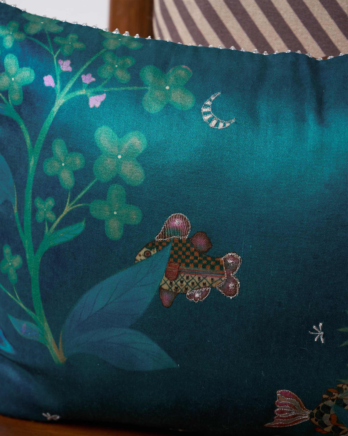 Close-up of Fern Cushion Cover showing a small patterned figure on deep teal fabric.