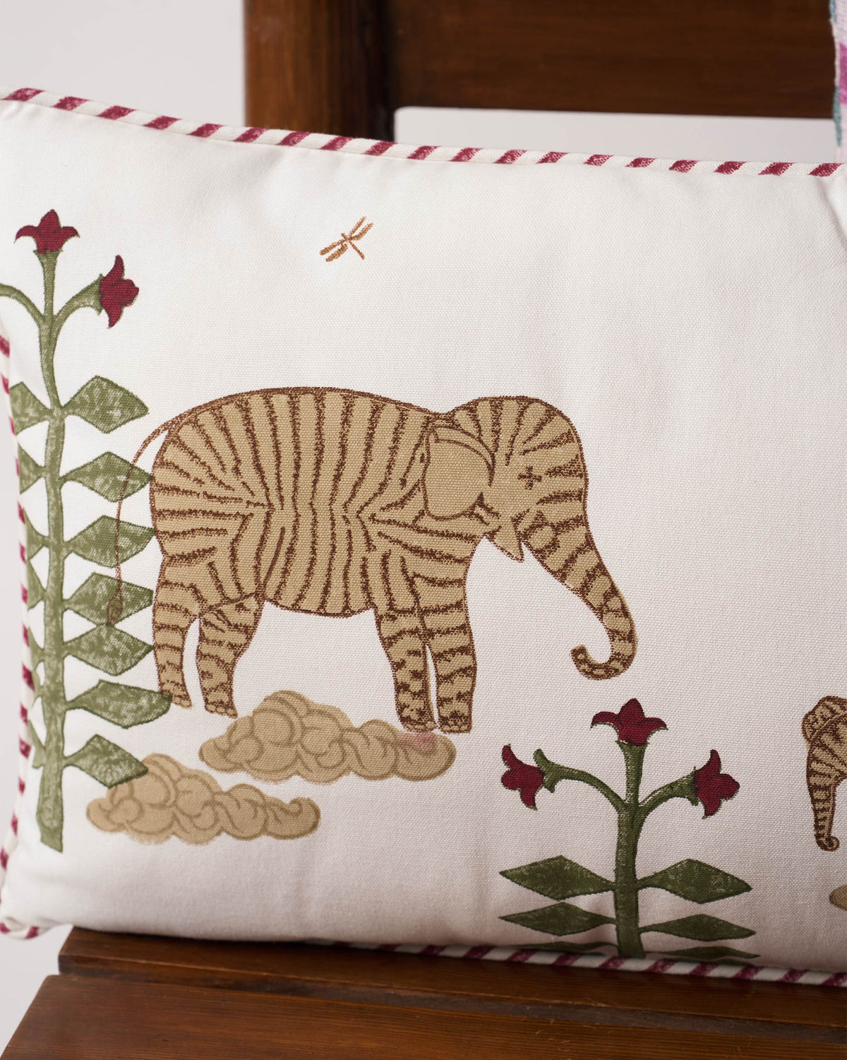 Close-up of Ele in Bloom Cushion Cover showing a striped elephant and red-topped flowers.