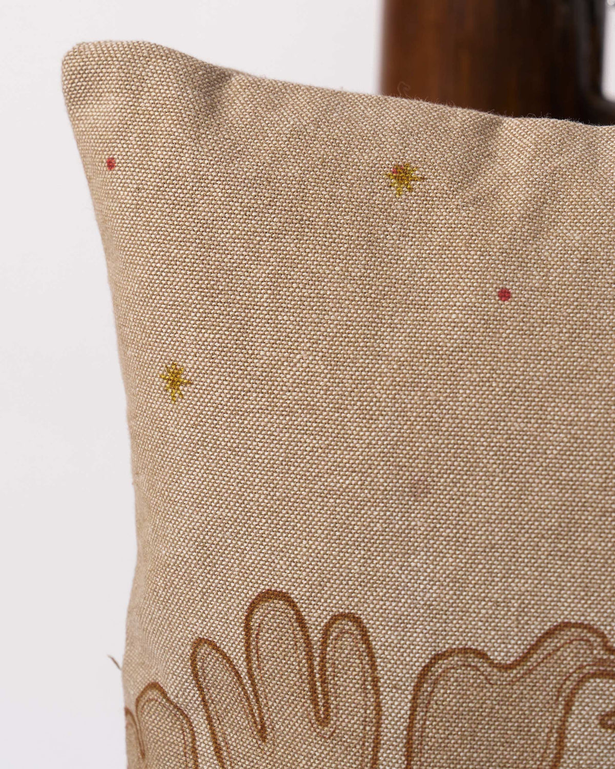Close-up of the Pomme Cushion Cover corner with gold star and red dot accents.