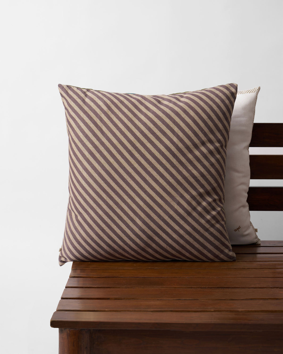 Brown and cream diagonal-striped cushion on a wooden bench.