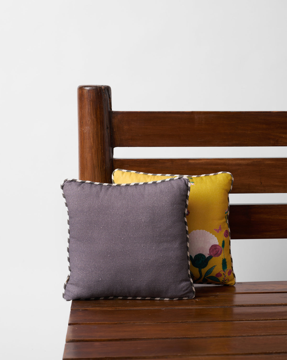 Back of a charcoal Peony car cushion with black-and-white striped piping.
