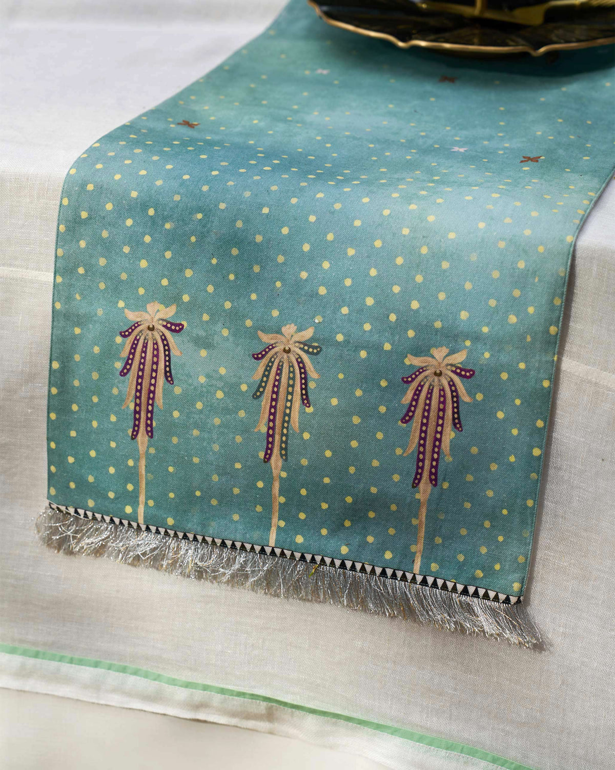 Yamuna table runner laid across a table with a gold dot pattern.