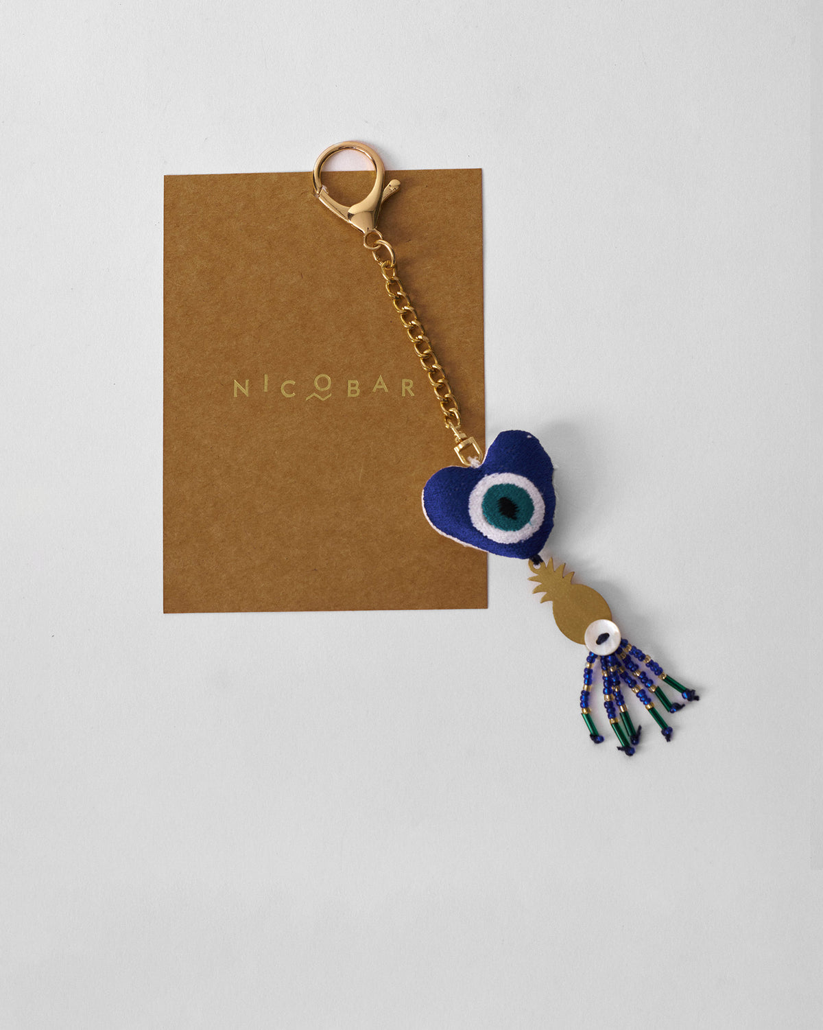 Ananas charm keychain with a blue evil eye heart and gold pineapple.