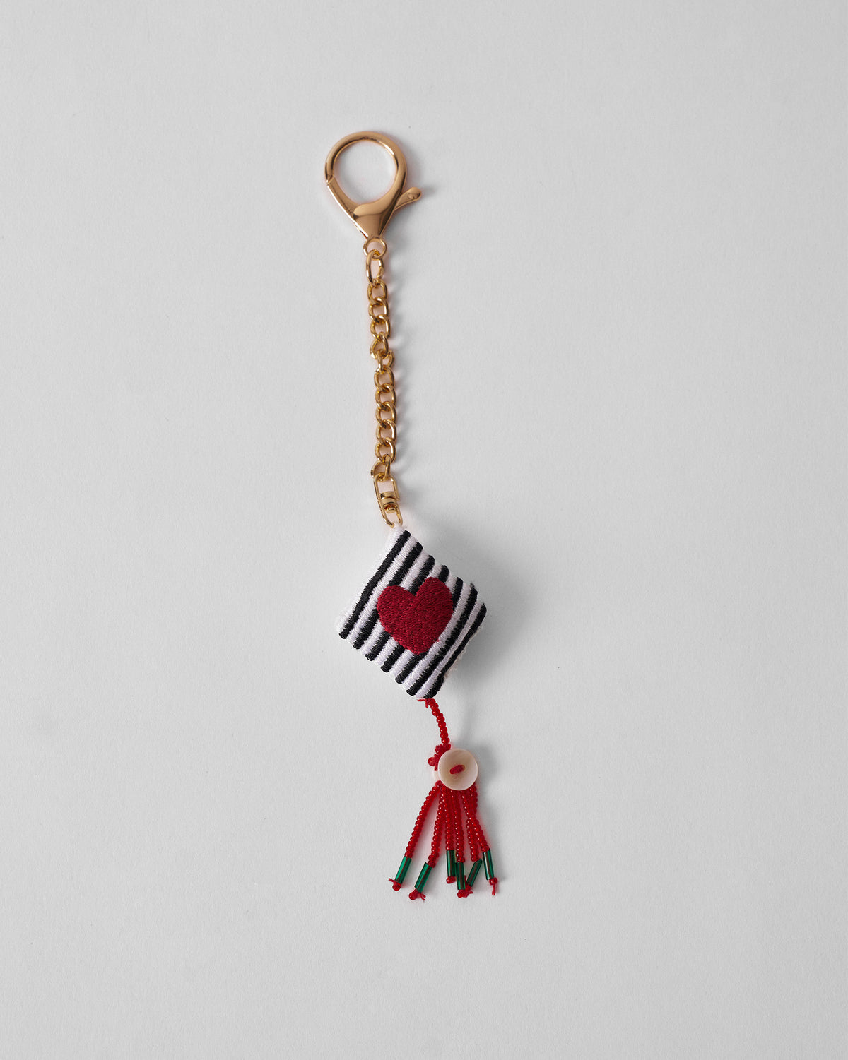 Dil charm with a red heart on a striped cube and a red tassel.