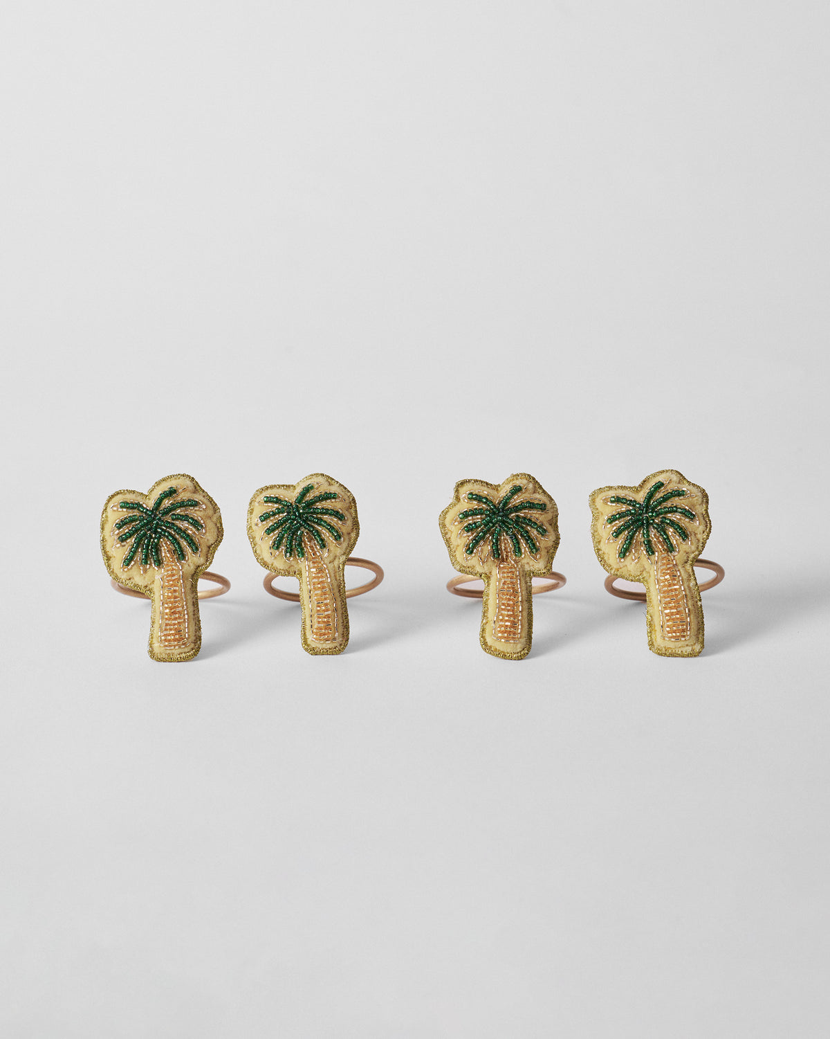 Set of four Palm napkin rings with beaded palm tree motifs.