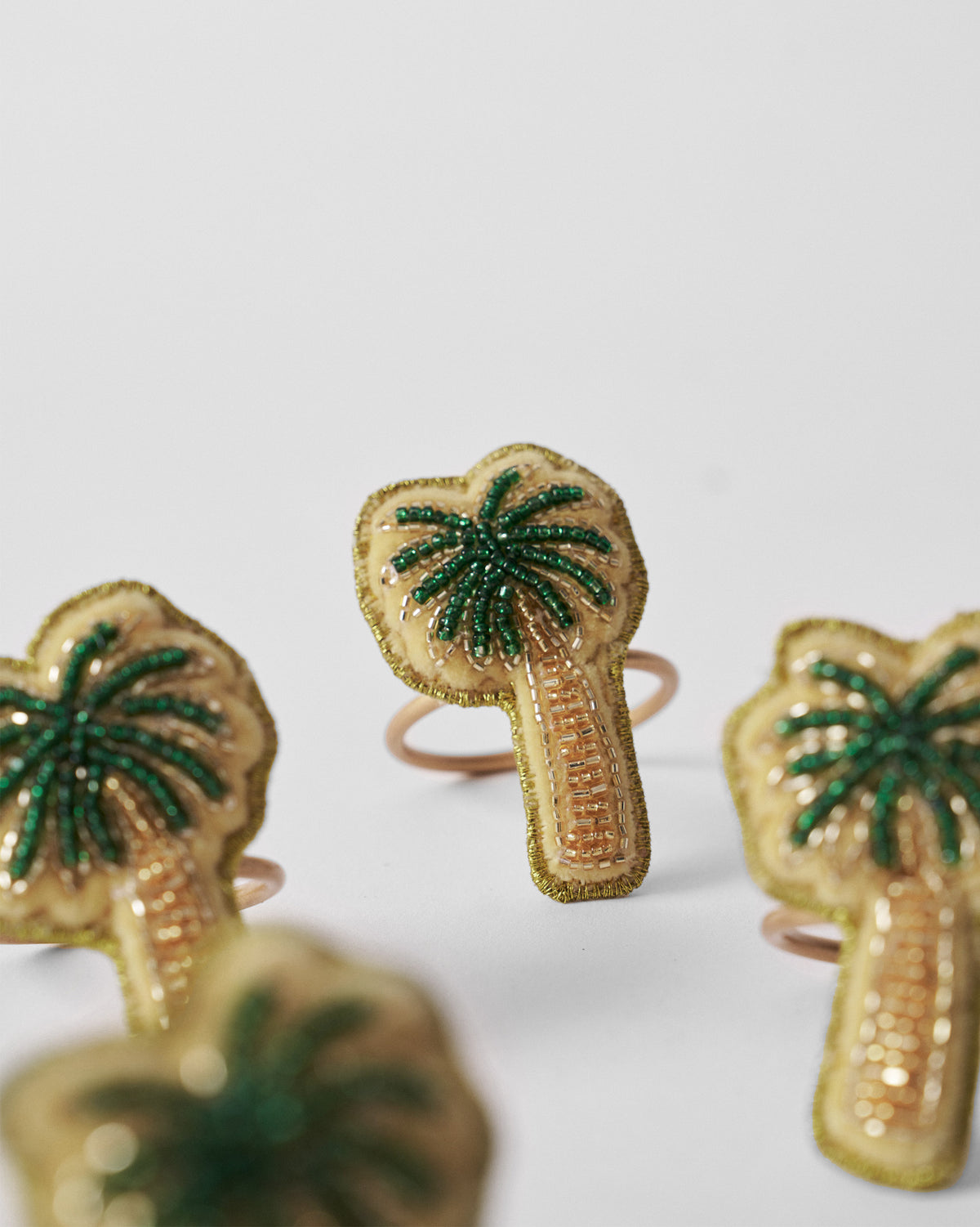 Close-up of a Palm napkin ring with green and gold beadwork.