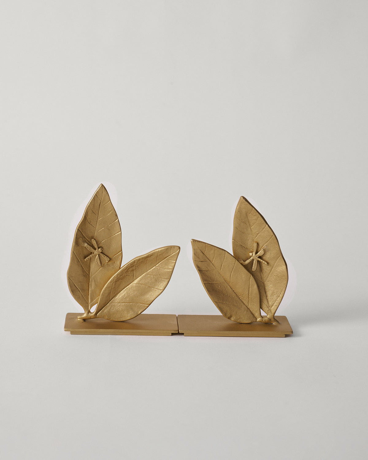 Pair of gold Mogra bookends with leaf forms and dragonflies.