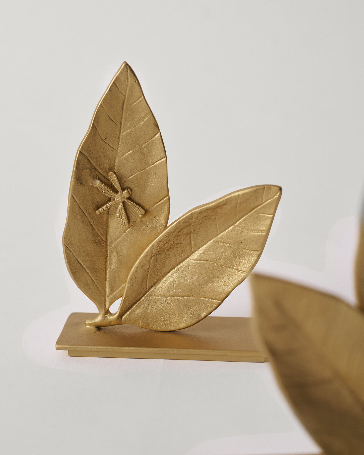 Gold Mogra bookend with veined leaves and a dragonfly.