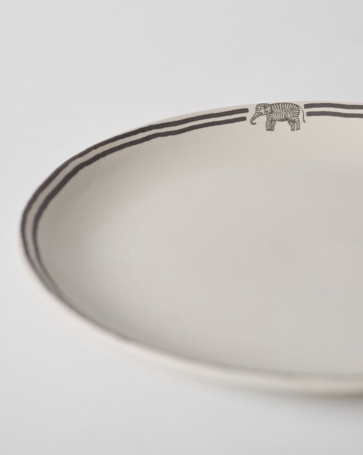 Close-up of a Tusk Dinner Plate rim with a small striped elephant motif.