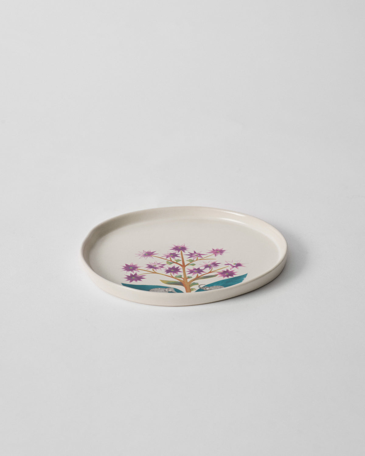 Mogra Dessert Plate with purple flowers and teal leaves, seen at an angle.