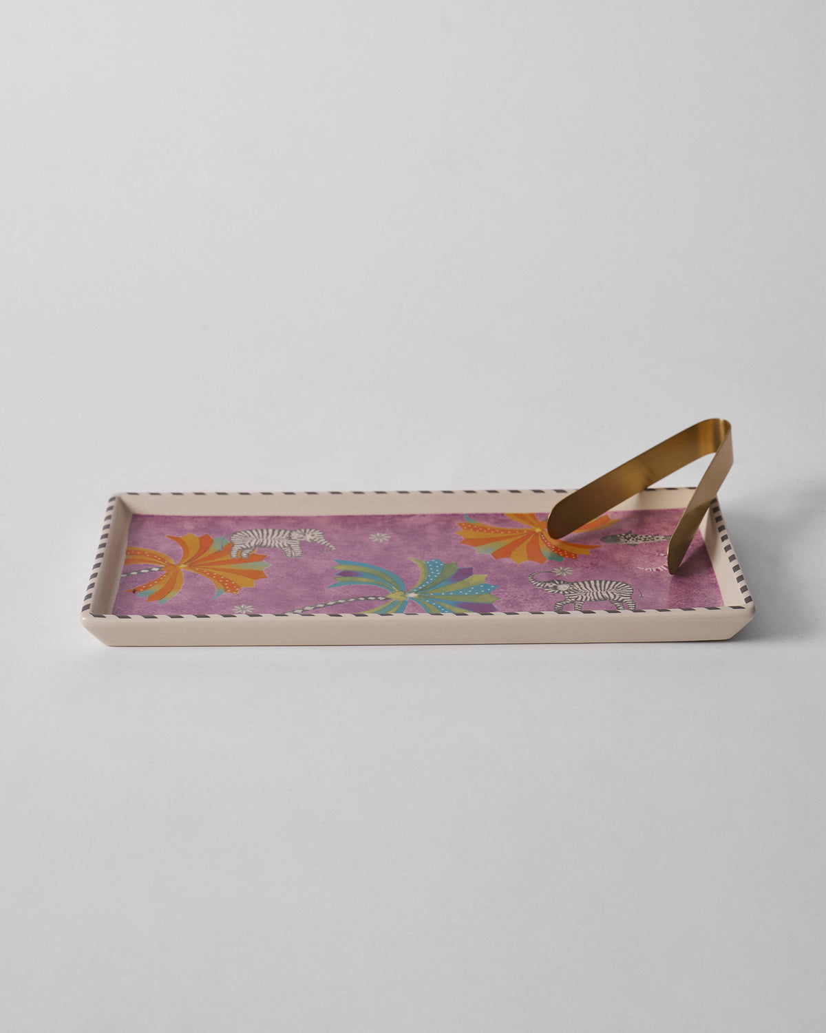 Tusk cookie tray with zebra-striped elephants and brass tongs.