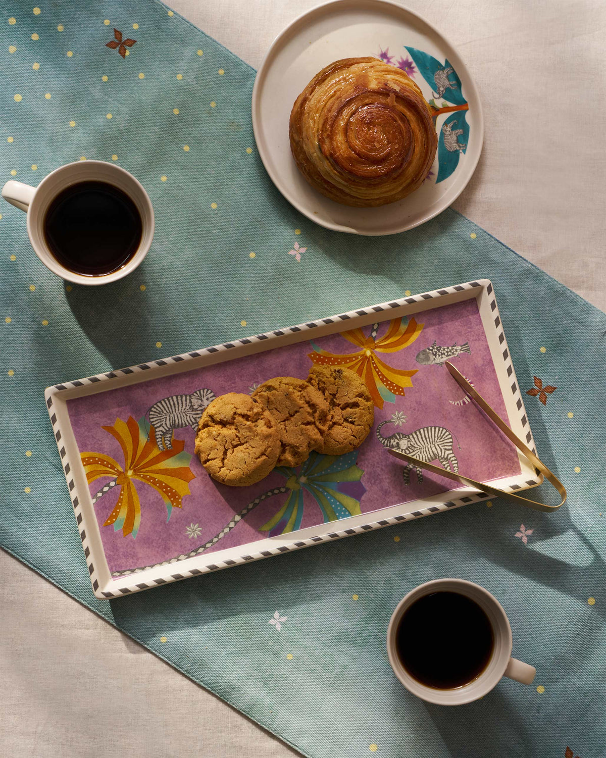 Tusk cookie tray served with cookies and tongs on a table.